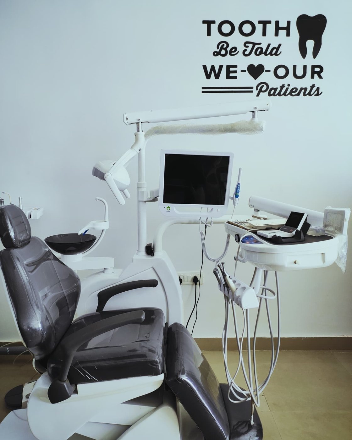 The treatment chair below a wall decal reading Tooth Be Told, We Love Our Patients